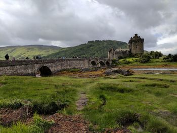 Old ruins on landscape against cloudy sky