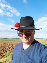 Portrait of man wearing sunglasses on field against sky