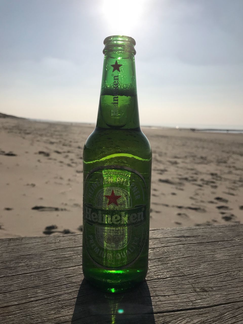 CLOSE-UP OF BEER BOTTLE ON TABLE AT BEACH