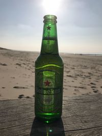 Close-up of beer bottle on table at beach against sky