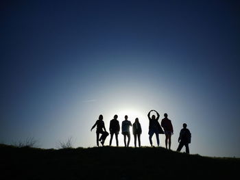 Silhouette people on field against clear sky