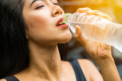 Close-up portrait of a young woman drinking glass