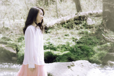 Portrait of young woman standing against trees