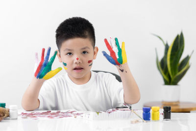 Portrait of boy holding multi colored umbrellas on table