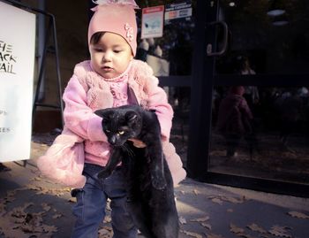 Cute girl carrying black cat