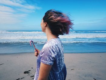 Side view of young woman standing at beach