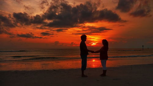 Silhouette woman on beach against sky during sunset