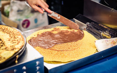 Close-up of person spreading chocolate on pancake at kitchen