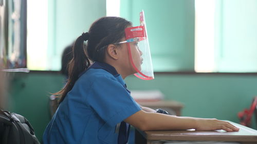 Side view of girl wearing face shied sitting at shield