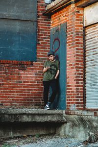 Teenage boy standing against brick wall