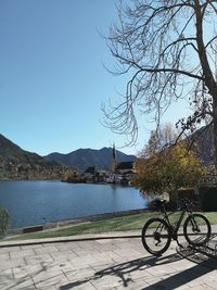 Bicycle by lake in city against clear sky