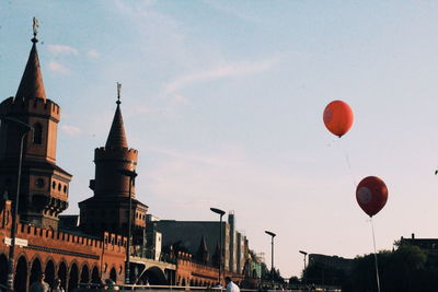 Low angle view of balloons and buildings against sky