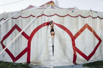 Circus performers peeking through circus tent entrance