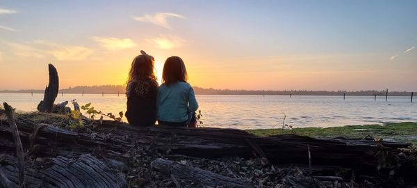 Rear view of woman looking at sea against sky during sunset