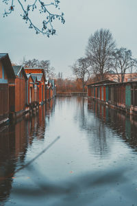 Wooden posts on river by building against sky