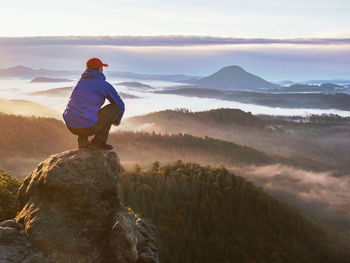 Rear view of man looking at mountains against sky