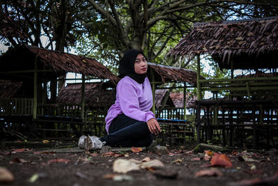 Portrait of young woman sitting on land