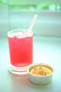 Close-up of red drink with cupcake on table in bakery