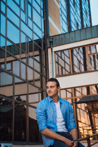 Young man standing by railing against building