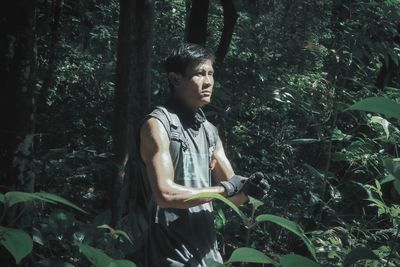 Young man looking away in forest