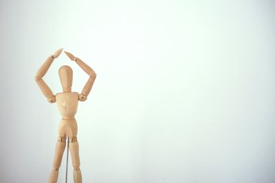 Woman standing by wall against white background