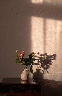 Flower vase on table against wall at home