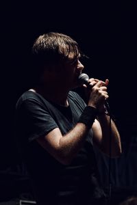 Midsection of man with arms raised against black background