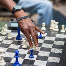 Midsection of man holding chess piece while playing chess outdoors