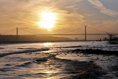 View of suspension bridge over sea during sunset
