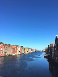 Houses by sea against clear blue sky