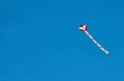 Low angle view of flag flying against clear blue sky