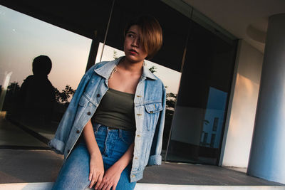 Portrait of young woman standing against wall