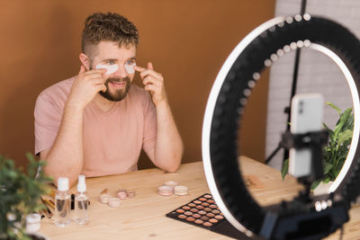 Side view of man using mobile phone while sitting on table