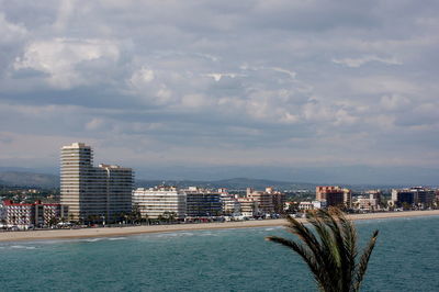 City buildings by sea against sky