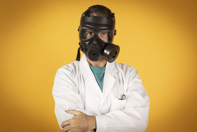 Portrait of man wearing gas mask against orange background