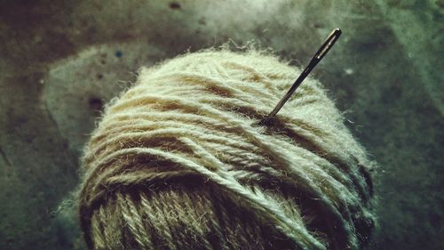 Close-up of sewing needle in wool on table