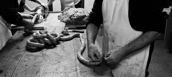 Midsection of men making pork sausage roll