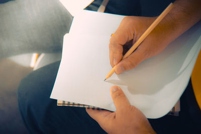 Midsection of man holding paper