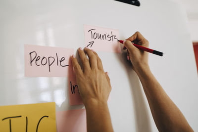 Hands of businesswoman writing on whiteboard while planning at creative office