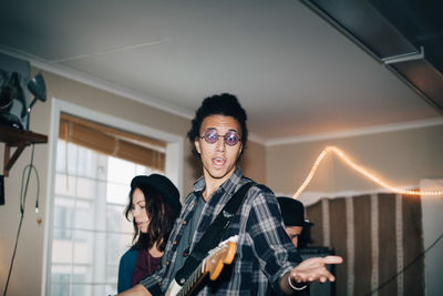 Male musician singing while playing instruments with friends at studio