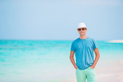 Young man standing at beach against sky