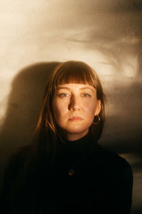 Portrait of beautiful young woman standing against wall