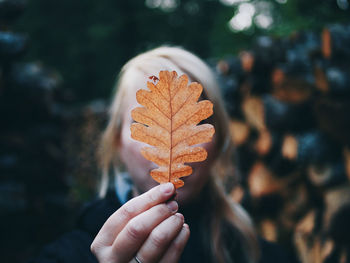 Close-up of woman covering face with leaf during autumn