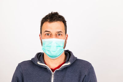 Portrait of man covering face against white background