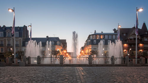 Illuminated buildings in city against clear sky