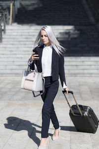 Young businesswoman on the go in the city checking cell phone