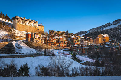 Sunset light illuminating soldeu town ski slopes and snow capped mountains, andorra