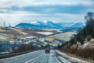 Road amidst snowcapped mountains against sky