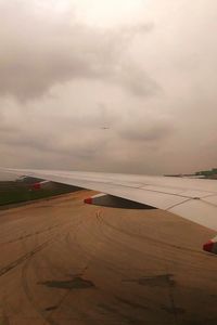 Airplane flying over airport runway against sky