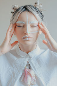 Close-up of woman with painted face against white background